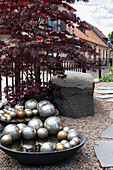 Schalen mit Silberkugeln, japanischer Ahorn und Granitblock am Gartenweg entlang