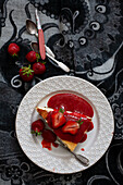 A slice of cheesecake with strawberry puree