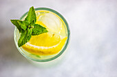 Mojito-Cocktail mit Minze und Zitrone, serviert im Kristallglas auf Betontisch