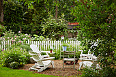 Weiße Gartenstühle auf Kiesterrasse im Garten
