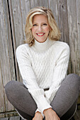 Mature blonde woman in white knitted jumper and grey leggings