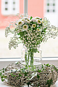 Weißer Blumenstrauß in einer Vase vor einem Fenster
