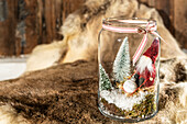 Ein Glas gefüllt mit Tannenbäumchen und einem Wichtel, Weihnachtsdekoration