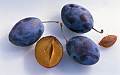 Plums, whole and halved on a light background