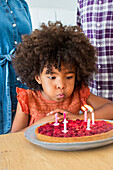 Girl blowing out candles on pie