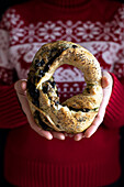 Woman wearing christmas weater holding christmas savory yeast wreath with mushroom filling