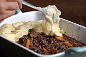 Preparing Shepherds Pie: spreading mashed potatoes over the mince mixture