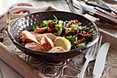 Baked salmon served with salad with cucumber and sun-dried tomatoes