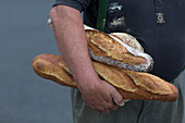 Mann trägt verschiedene Brote unter dem Arm