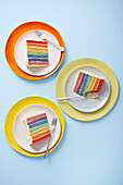 Regenbogentorte - drei Stücke auf Tellern