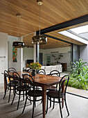 View from dining room with wooden table and Thonet chairs to living room and courtyard