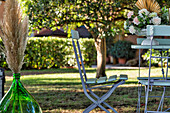 Tisch mit Rosengesteck und Stühle im Garten