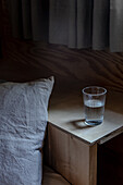 A glass of water on the bedside table behind the bed