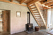 Tiled wood stove under wooden stairs in renovated country house