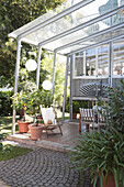 Überdachte Terrasse mit Kübelpflanzen, Lampions, Sonnenschirm und Essplatz