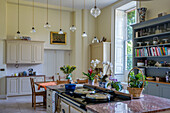 Modernized English country house kitchen with cooking island, sideboard and Pedant glass lamps