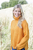 Junge blonde Frau in gelbem Rollkragenpullover in der Natur