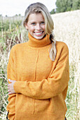 Junge blonde Frau in gelbem Rollkragenpullover in der Natur