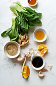 Ingredients for cooking an asian cuisine dish on a marble table Fresh bok choy, sliced orange and condiments