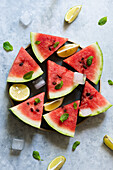 Wassermelonenstücke mit Zitronenspalten und Minzblättchen auf Teller