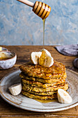 Stack of banana pancakes topped with sliced banana and a drizzle of honey