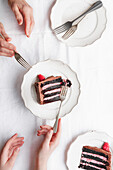 Raspberry and chocolate cake slices, on plates with forks