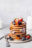 Pancake stack served with blueberries, strawberries, banana and edible flowers