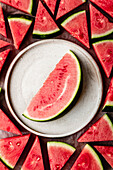 Watermelon slice on a ceramic plate surrounded with smaller watermelon slices