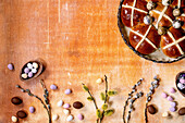 Homemade Easter traditional hot cross buns in ceramic dish with blossom willow branches and chocolate eggs candies