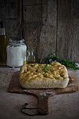 Easy recipe rosemary focaccia on a wooden cutting board, decorated with rosemary