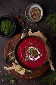 A bowl of beetroot soup garnished with cream, dill, pumpkin and chia seeds