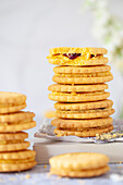 Stacks of custard cream style sandwich biscuits filled with buttercream and jam.