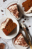 Slicces of coffee cake on tea plates, topped with whipped cream and grated chocolate