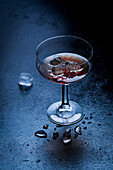 Glass goblet of red wine with cubes of ice placed on wet table