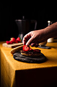 Hand placing piece of fresh strawberry on bagel with chocolate paste