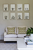 White loveseat with cushions, with a picture gallery with a dog motif above it
