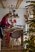 Frau am gedeckten Tisch in weihnachtlich dekoriertem Essbereich