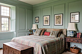 Queen bed with wool and silk bedspread in a bedroom with coffered walls