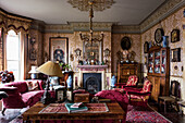 Velvet furniture and antiques in a Victorian room with ornamental wallpaper