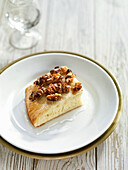 A piece of aniseed cake with walnuts on a plate