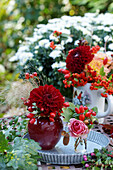 Herbsttisch mit Dahlie, Rose, Hagebutte und Eicheln