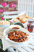 Grilled pulled pork with bread and coleslaw on a garden table