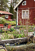 Pond in the cottage garden, red-brown wooden house in the background