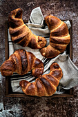 Croissants with a linen cloth on a wooden tray