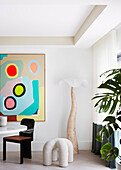 Designer floor lamp and sculpture in a dining area, modern art on wall