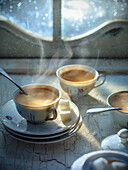 Steaming cups of coffee in front of a window