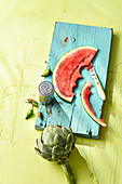 Artischocke und eine angebissene Scheibe Wassermelone