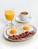 Frühstück mit Bacon, Spiegeleiern, Orangensaft und Kaffee