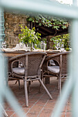 Rustic wooden table and rattan chairs on brick terrace