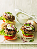 Mini burger with lettuce leaf, tomato, and red onion, served with sour cream and mint